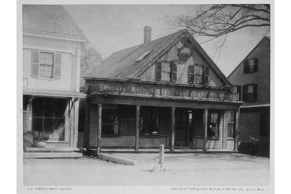 A black and white historical photo of Quincy Mutual's building- a small, two-story wooden structure with a covered porch. = https://www.quincymutual.com/index.htm