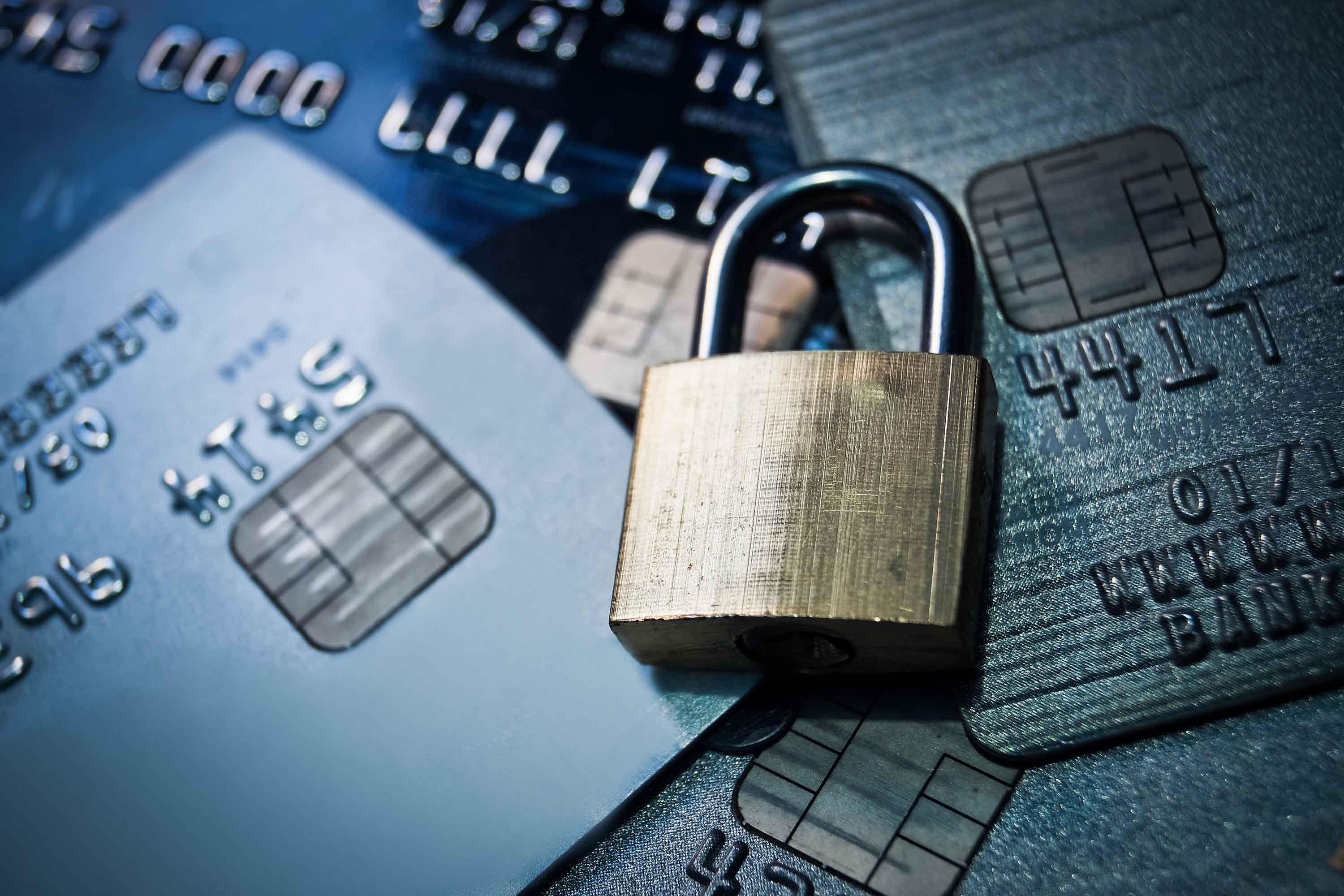 A brass padlock laying on a stack of credit cards. = https://www.quincymutual.com/index.htm