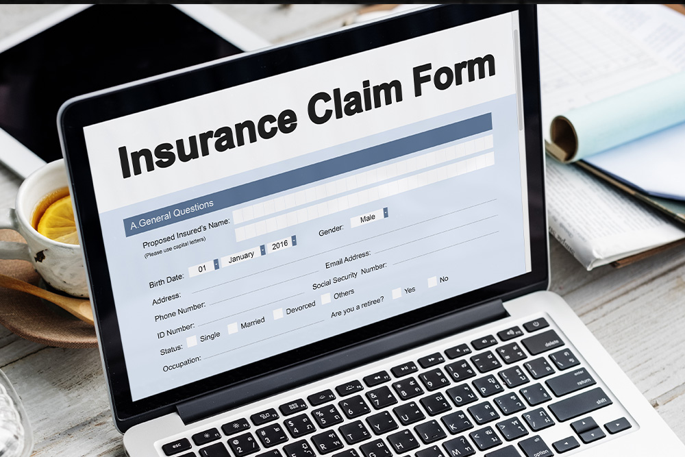 A laptop displays an insurance claim form titled “Insurance Claim Form,” with fields for personal information like name, birth date, gender, and contact details - https://www.quincymutual.com/index.htm