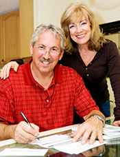 Older couple at dining room table filling out documents. = https://www.quincymutual.com/index.htm