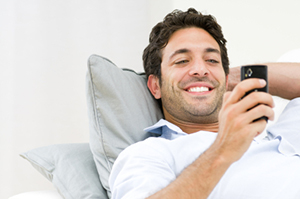 Man laying on couch smiling at the phone he's holding in his hand. - https://www.quincymutual.com/
