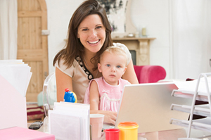 Mother with child on her lap at her work desk with her laptop open. Mother with child on her lap at her work desk with her laptop open. = https://www.quincymutual.com/index.htm