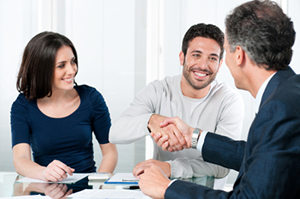 Man and woman seated at table; the man is shaking hands with an agent. style = https://www.quincymutual.com/index.htm